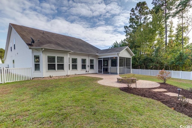 rear view of house featuring a lawn, a sunroom, and a patio