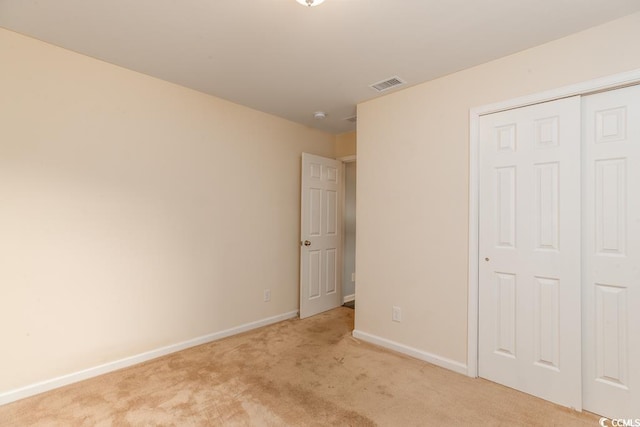 unfurnished bedroom featuring light carpet and a closet