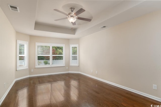 unfurnished room with hardwood / wood-style flooring, ceiling fan, and a tray ceiling