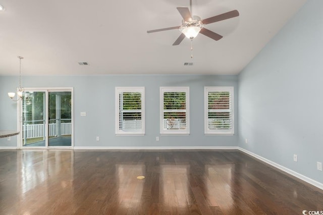 unfurnished room with ceiling fan with notable chandelier and dark wood-type flooring