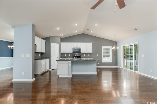 kitchen featuring appliances with stainless steel finishes, tasteful backsplash, ceiling fan with notable chandelier, a center island with sink, and white cabinetry