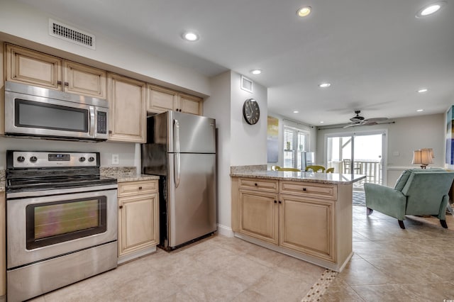 kitchen featuring appliances with stainless steel finishes, kitchen peninsula, light stone counters, and ceiling fan