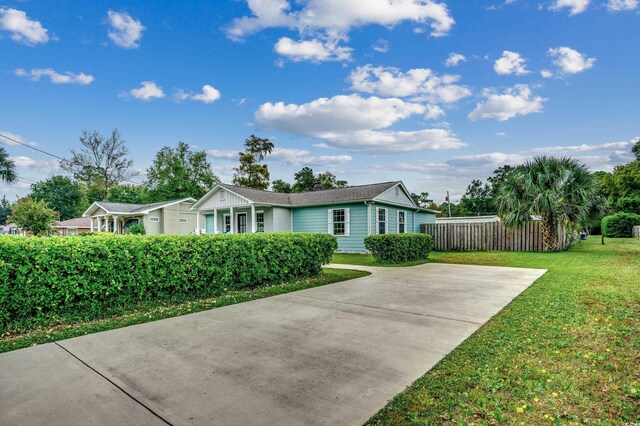 ranch-style home with a front yard and fence
