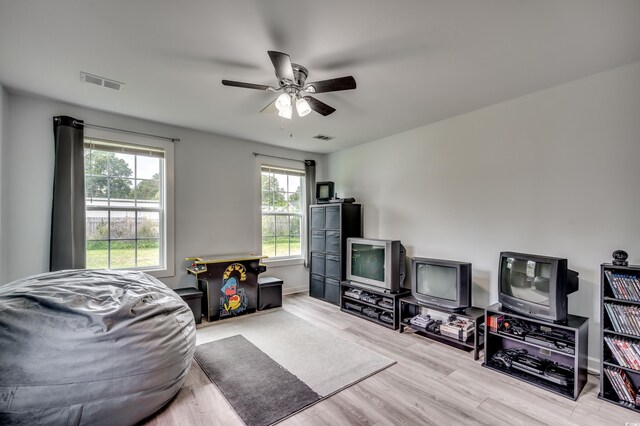 living area with visible vents, wood finished floors, baseboards, and ceiling fan