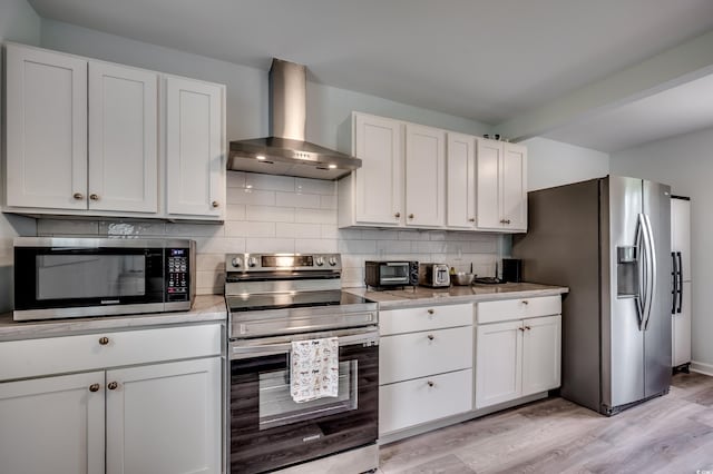 kitchen with white cabinetry, appliances with stainless steel finishes, wall chimney exhaust hood, and light hardwood / wood-style floors