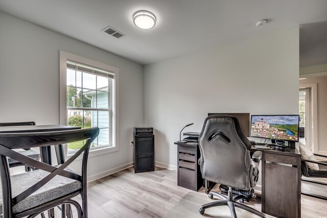 home office with baseboards, light wood-type flooring, and visible vents