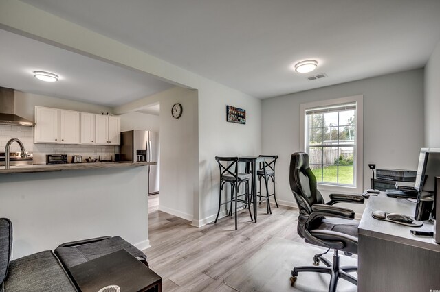 office area with baseboards, a toaster, light wood-style flooring, and visible vents
