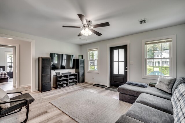 living area featuring light wood finished floors, visible vents, baseboards, and ceiling fan