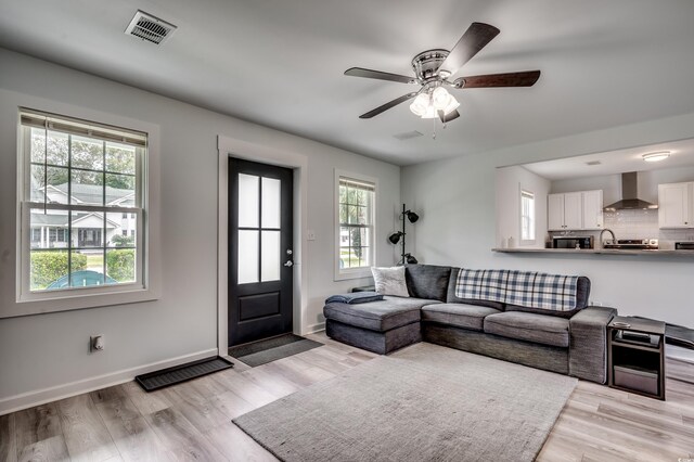 living area with ceiling fan, light wood-type flooring, and visible vents