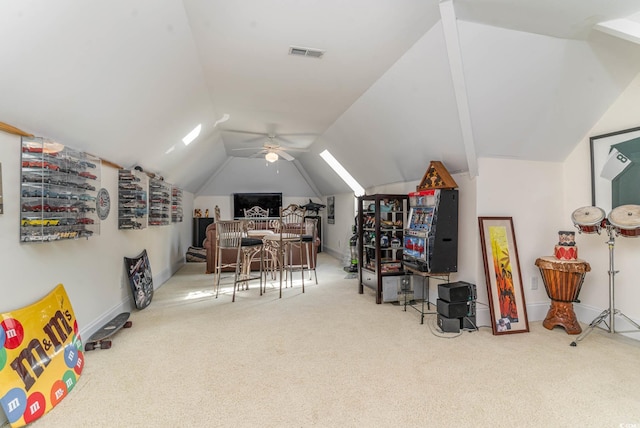 carpeted home office featuring ceiling fan, lofted ceiling with skylight, visible vents, and baseboards