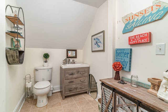 bathroom featuring lofted ceiling, toilet, vanity, tile patterned flooring, and baseboards