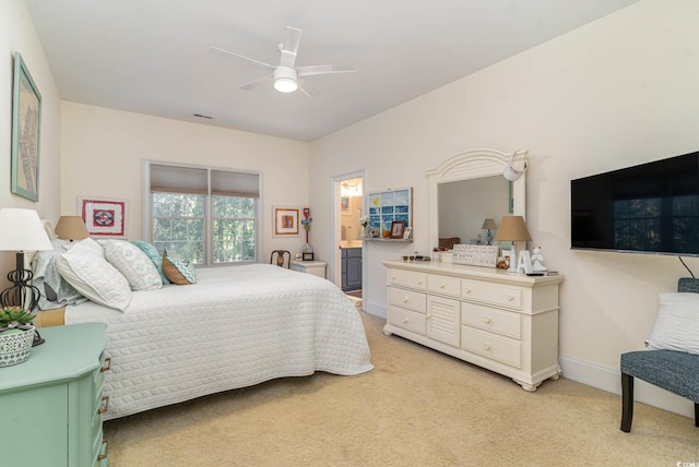 bedroom with a ceiling fan, light carpet, ensuite bath, and baseboards