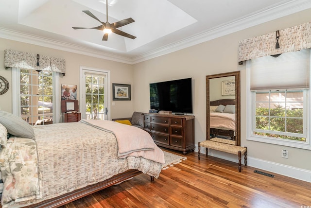 bedroom featuring baseboards, visible vents, a raised ceiling, wood finished floors, and access to exterior