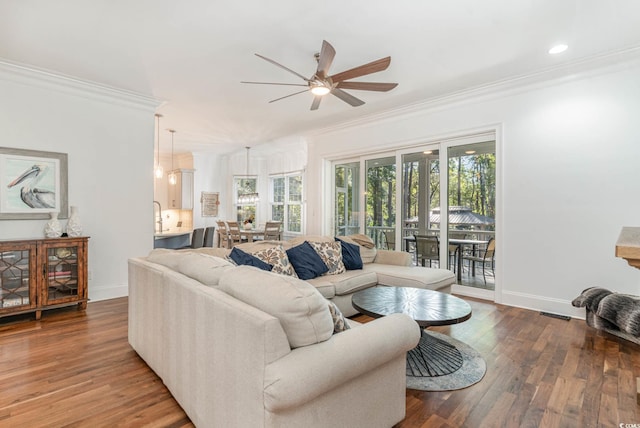 living room featuring baseboards, ceiling fan, wood finished floors, and crown molding