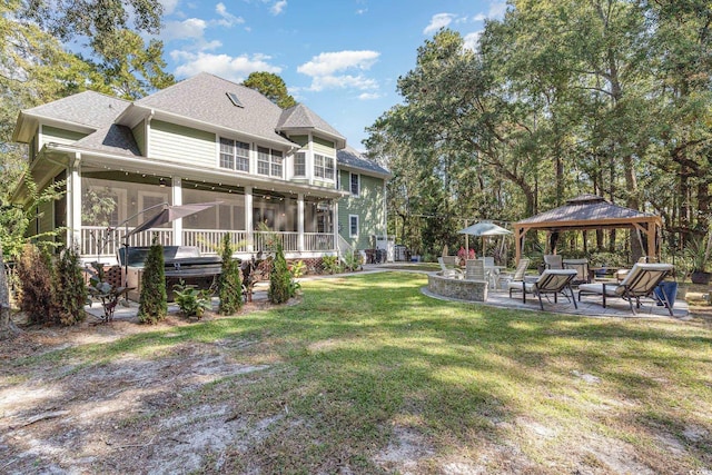 rear view of house featuring roof with shingles, a patio, a lawn, a gazebo, and a sunroom