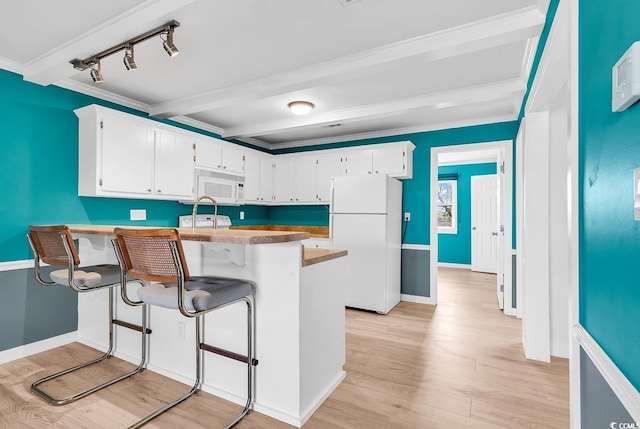 kitchen with white appliances, white cabinetry, a breakfast bar, and kitchen peninsula