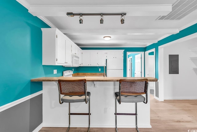 kitchen featuring electric panel, white appliances, a breakfast bar, and kitchen peninsula