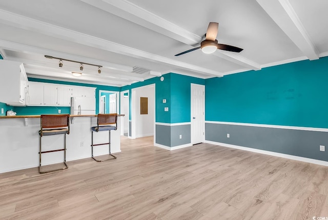 interior space with beamed ceiling, white refrigerator, light hardwood / wood-style floors, and white cabinets