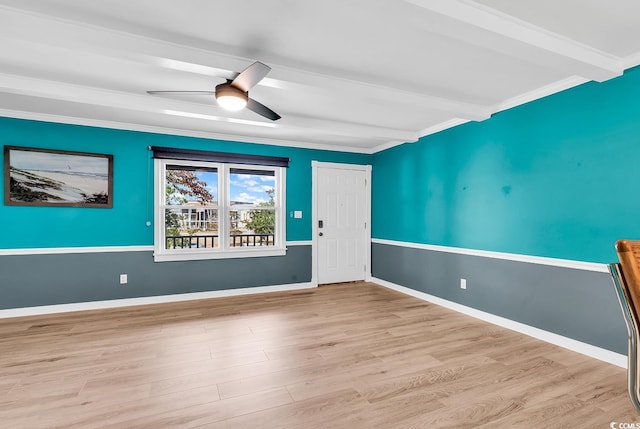 empty room featuring ceiling fan, light hardwood / wood-style floors, beamed ceiling, and ornamental molding