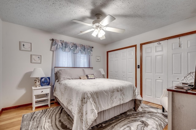 bedroom featuring ceiling fan, a textured ceiling, multiple closets, and light wood-type flooring