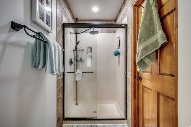 bathroom with a textured ceiling and a shower with door