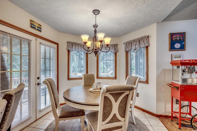 tiled dining room with a chandelier, a healthy amount of sunlight, and a textured ceiling