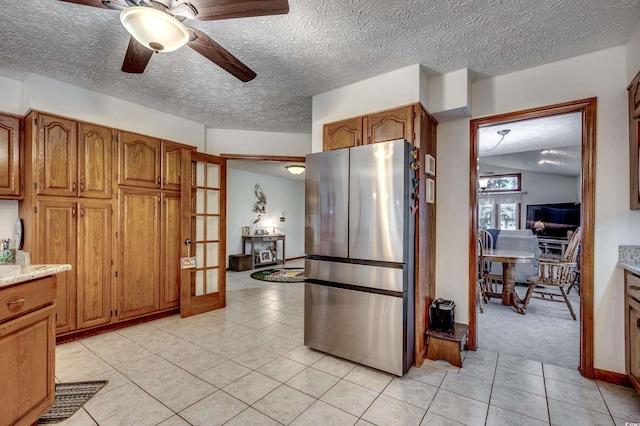 kitchen with a textured ceiling, light tile patterned flooring, ceiling fan, and stainless steel refrigerator