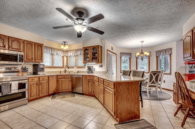 kitchen featuring kitchen peninsula, stainless steel appliances, hanging light fixtures, and a healthy amount of sunlight