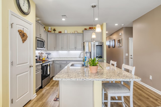 kitchen featuring sink, a kitchen breakfast bar, an island with sink, pendant lighting, and stainless steel appliances