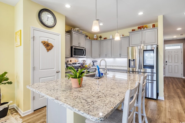 263 Red Maple Loop, Longs, SC 29568 - kitchen with a breakfast bar, light stone countertops, light wood finished floors, and stainless steel appliances