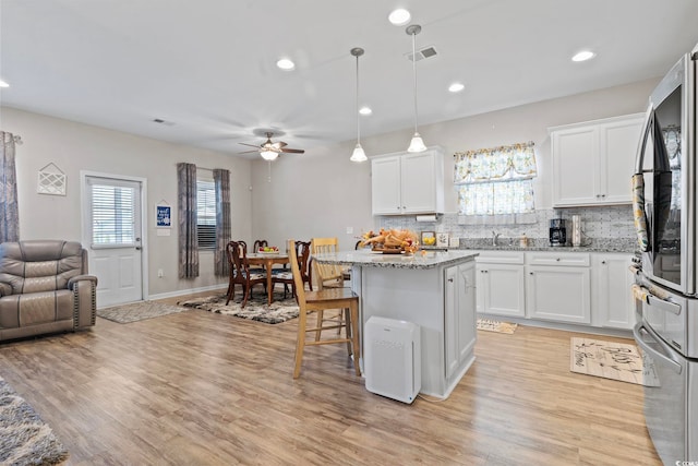 kitchen with white cabinets, a kitchen breakfast bar, a center island, and tasteful backsplash