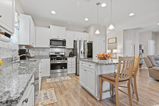 kitchen with white cabinets, hanging light fixtures, sink, and appliances with stainless steel finishes