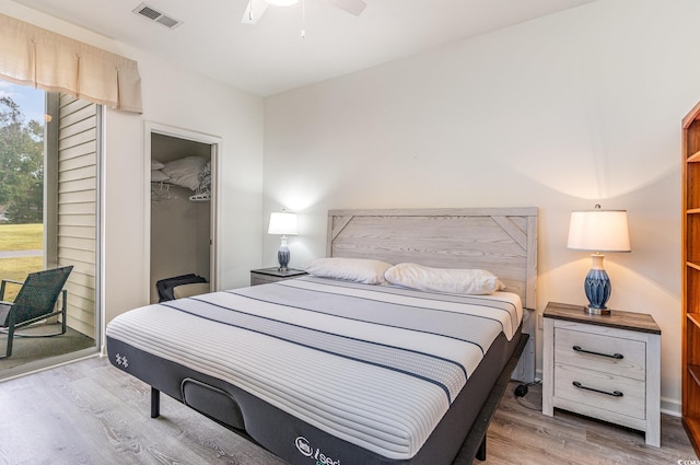 bedroom with ceiling fan, a closet, a spacious closet, and light hardwood / wood-style flooring