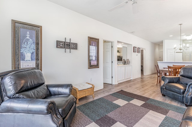 living room with light hardwood / wood-style flooring and ceiling fan with notable chandelier