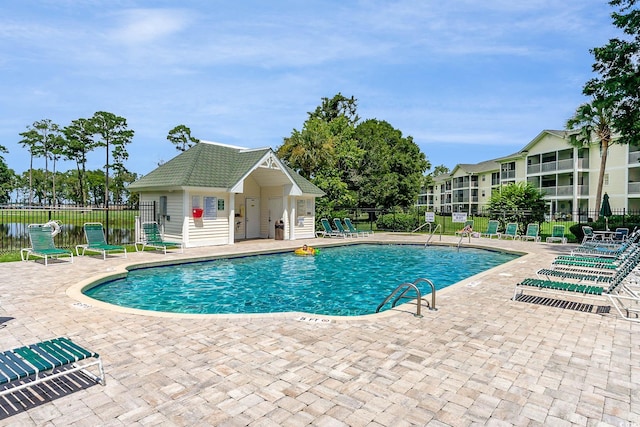 view of swimming pool featuring an outbuilding and a patio