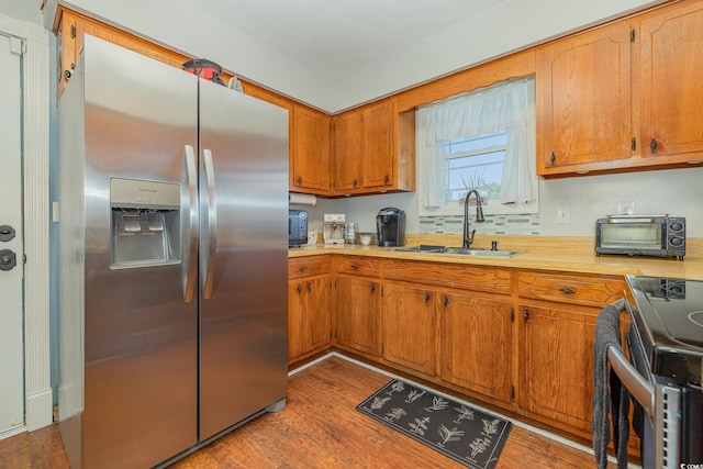 kitchen featuring sink, range, light hardwood / wood-style flooring, and stainless steel refrigerator with ice dispenser