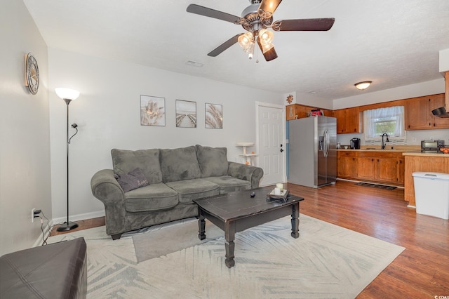 living room featuring ceiling fan, sink, and dark hardwood / wood-style flooring