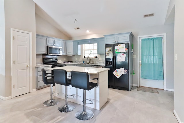 kitchen with sink, vaulted ceiling, a kitchen bar, a kitchen island, and black appliances