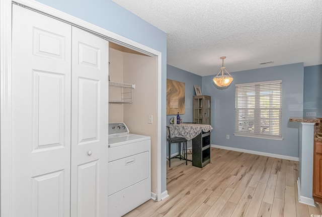 kitchen featuring a textured ceiling, pendant lighting, light hardwood / wood-style floors, and washer / clothes dryer