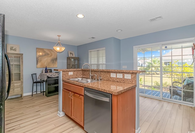 kitchen featuring a kitchen island with sink, stainless steel dishwasher, light hardwood / wood-style flooring, pendant lighting, and sink