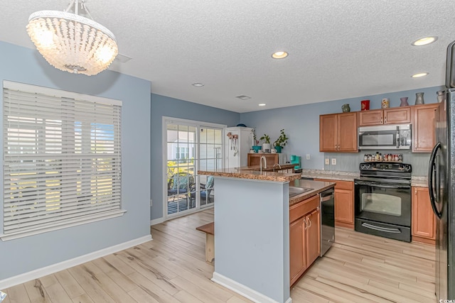 kitchen featuring a center island, hanging light fixtures, stainless steel appliances, light hardwood / wood-style flooring, and a chandelier