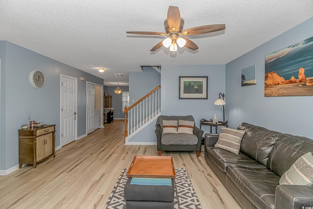 living room featuring light hardwood / wood-style flooring, a textured ceiling, and ceiling fan