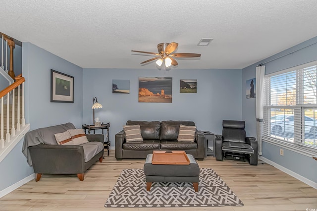 living room with a textured ceiling, light hardwood / wood-style floors, and ceiling fan