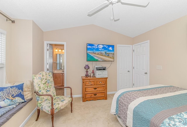 bedroom with light colored carpet, ceiling fan, lofted ceiling, and ensuite bath