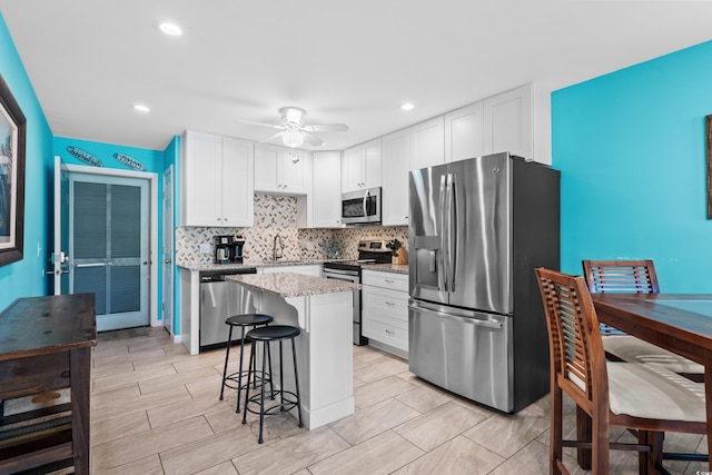 5601 N Ocean Blvd Unit C-202, Myrtle Beach, SC 29577 - kitchen featuring appliances with stainless steel finishes, tasteful backsplash, a breakfast bar, white cabinetry, and light stone countertops
