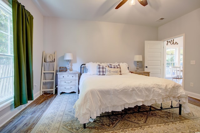 bedroom featuring multiple windows, hardwood / wood-style floors, access to outside, and ceiling fan