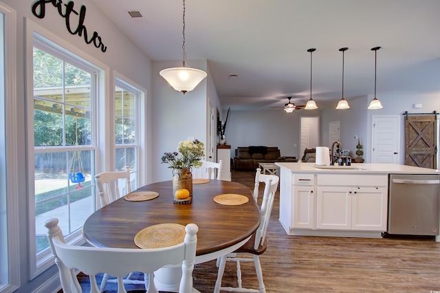 dining room featuring a barn door, light hardwood / wood-style floors, ceiling fan, and sink