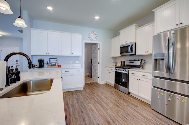 kitchen featuring white cabinets, appliances with stainless steel finishes, pendant lighting, and sink