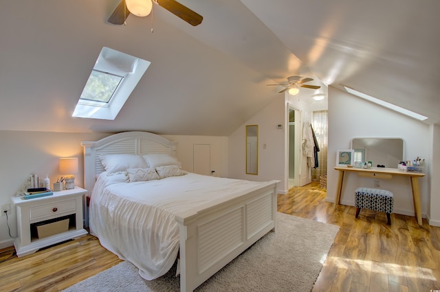 bedroom with vaulted ceiling with skylight, ceiling fan, and light wood-type flooring