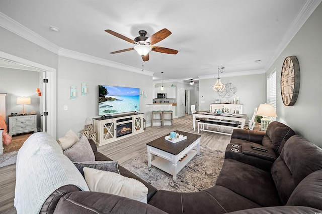 living room featuring ornamental molding, light hardwood / wood-style floors, and ceiling fan